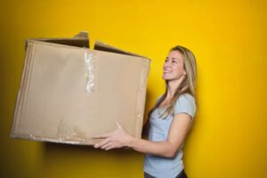 A woman is holding a large carton box. - something our Long Island movers can help you with